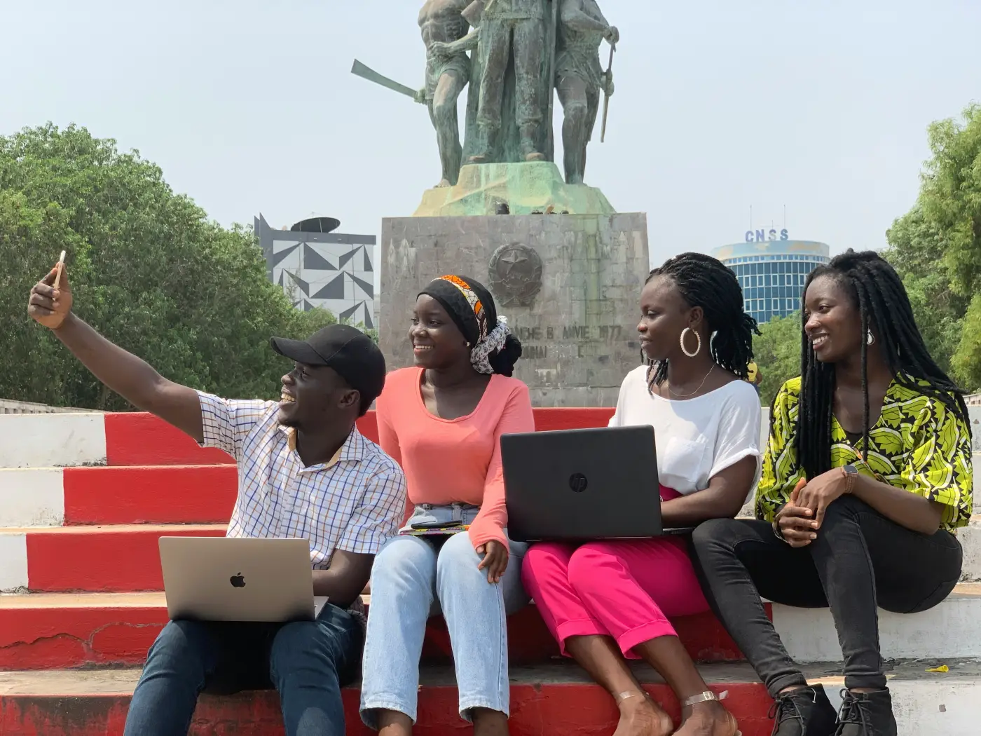 Young researchers with laptops gathering outside a civic monument